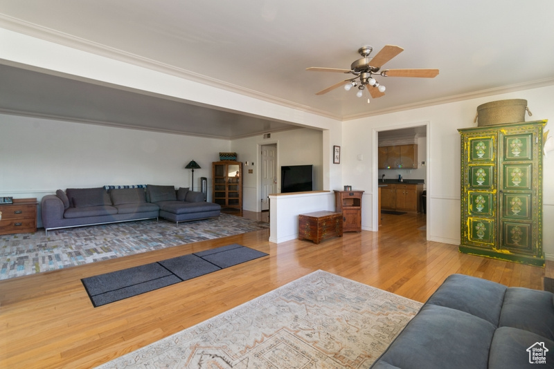 Living area with wood finished floors, ceiling fan, and ornamental molding