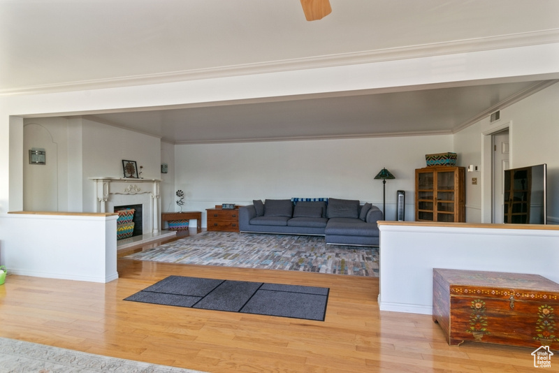 Living area with wood finished floors, a fireplace with raised hearth, and ornamental molding