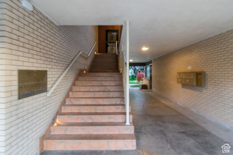 Staircase featuring brick wall