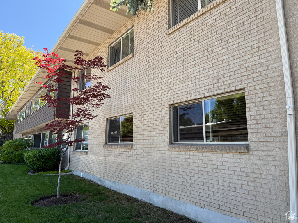 View of property exterior featuring brick siding and a yard