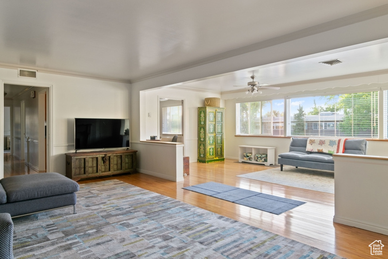 Living room with healthy amount of natural light, wood finished floors, and a ceiling fan