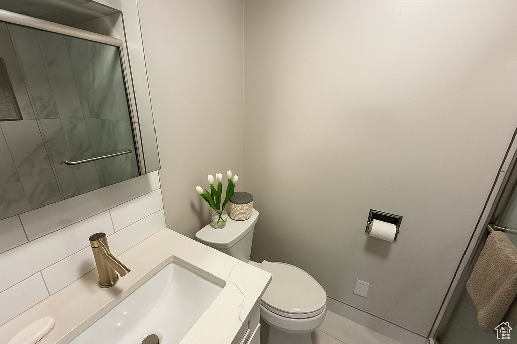 Full bath with toilet, vanity, an enclosed shower, and tile patterned floors