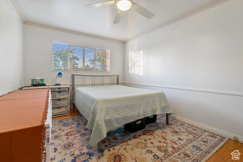Bedroom with crown molding, wood finished floors, and ceiling fan