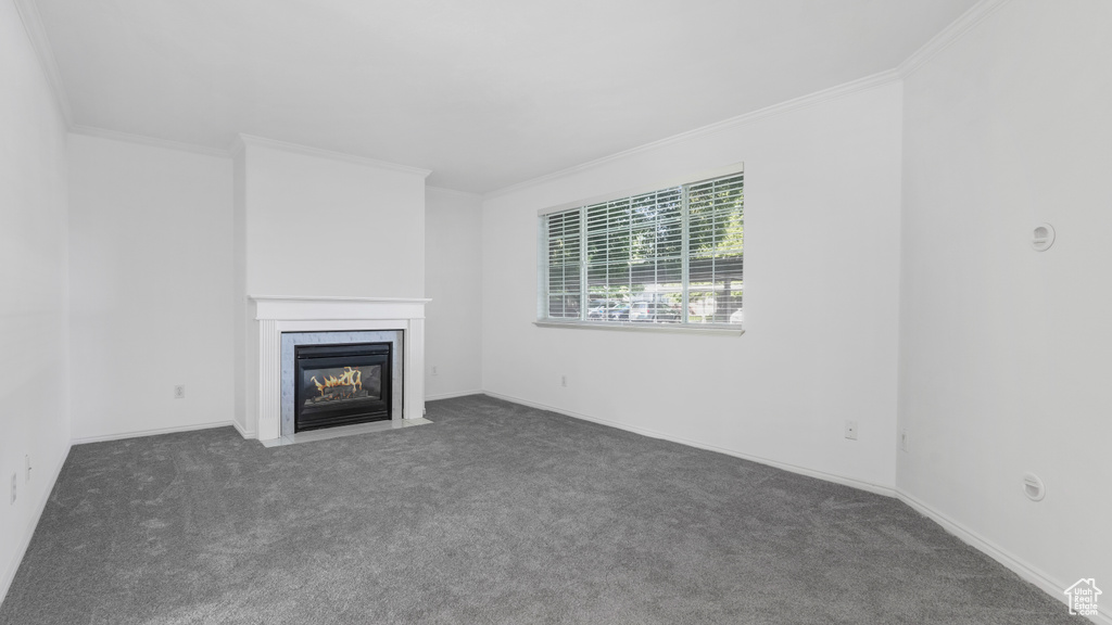 Unfurnished living room with crown molding, carpet flooring, a fireplace with flush hearth, and baseboards