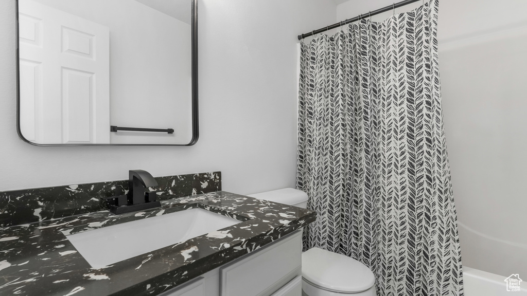 Full bathroom with toilet, vanity, and a shower with curtain