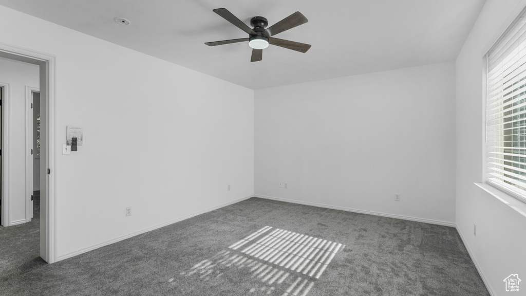 Carpeted spare room with a ceiling fan and baseboards