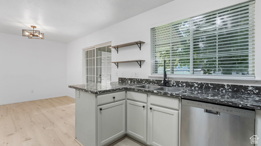 Kitchen featuring dishwasher, a sink, light wood-style flooring, open shelves, and a chandelier