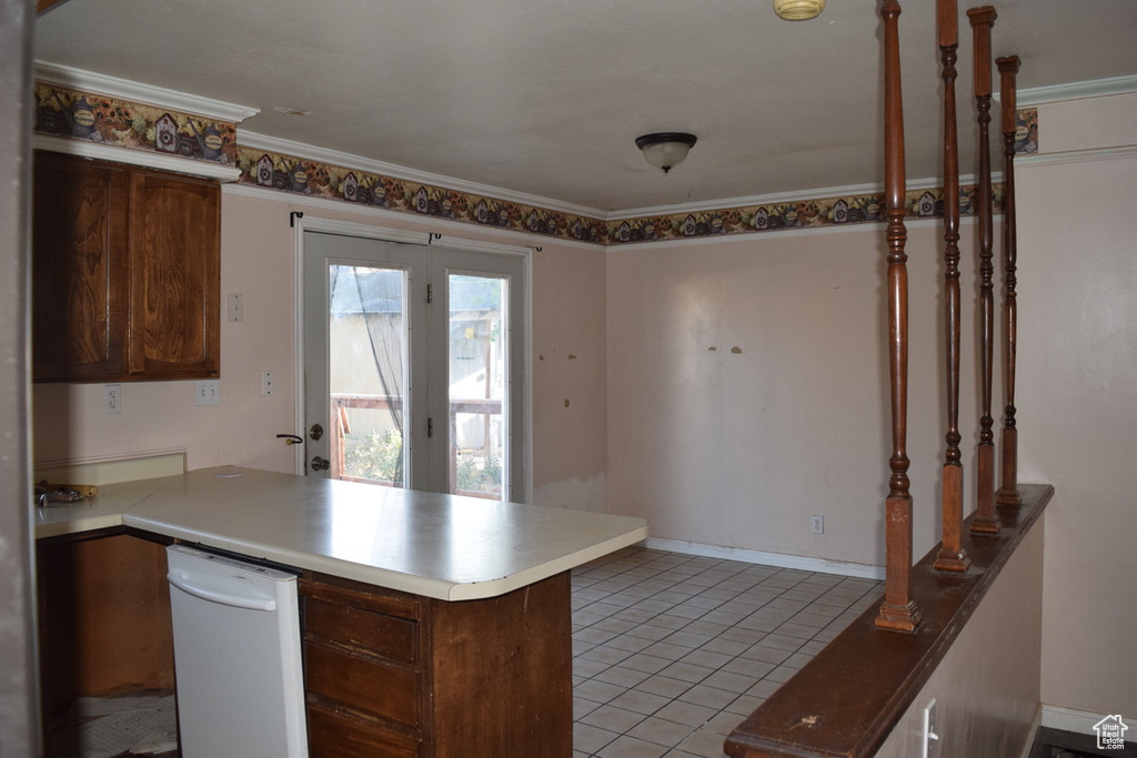 Kitchen with a peninsula, light tile patterned flooring, ornamental molding, and light countertops