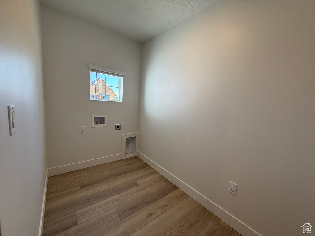 Laundry area featuring electric dryer hookup, light wood-style floors, baseboards, and hookup for a washing machine