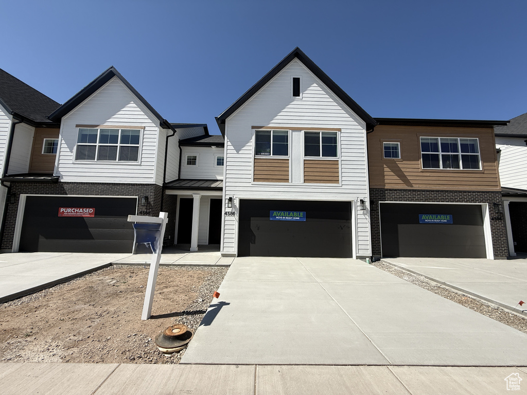 View of front of home with a garage, concrete driveway, and brick siding