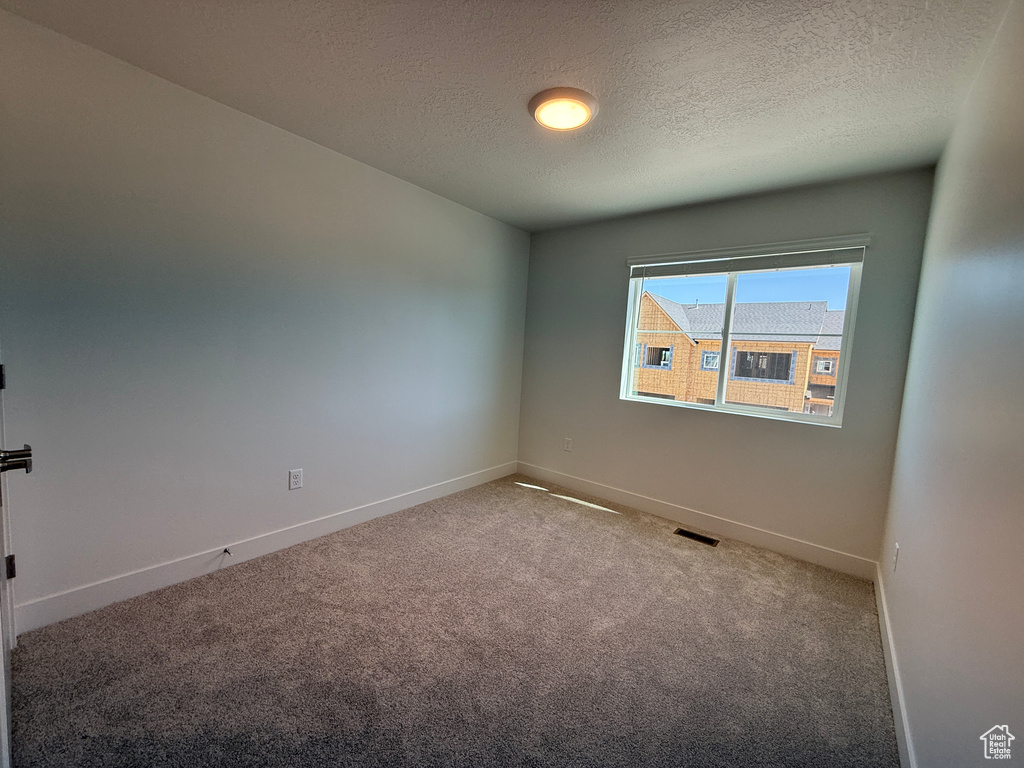 Carpeted spare room featuring baseboards and a textured ceiling