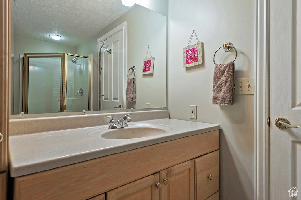 Bathroom with vanity, a shower stall, and a textured ceiling