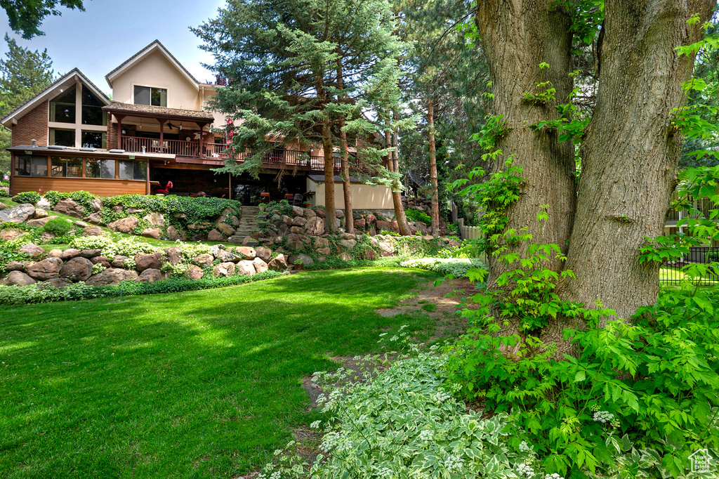 View of grassy yard with a wooden deck and a sunroom