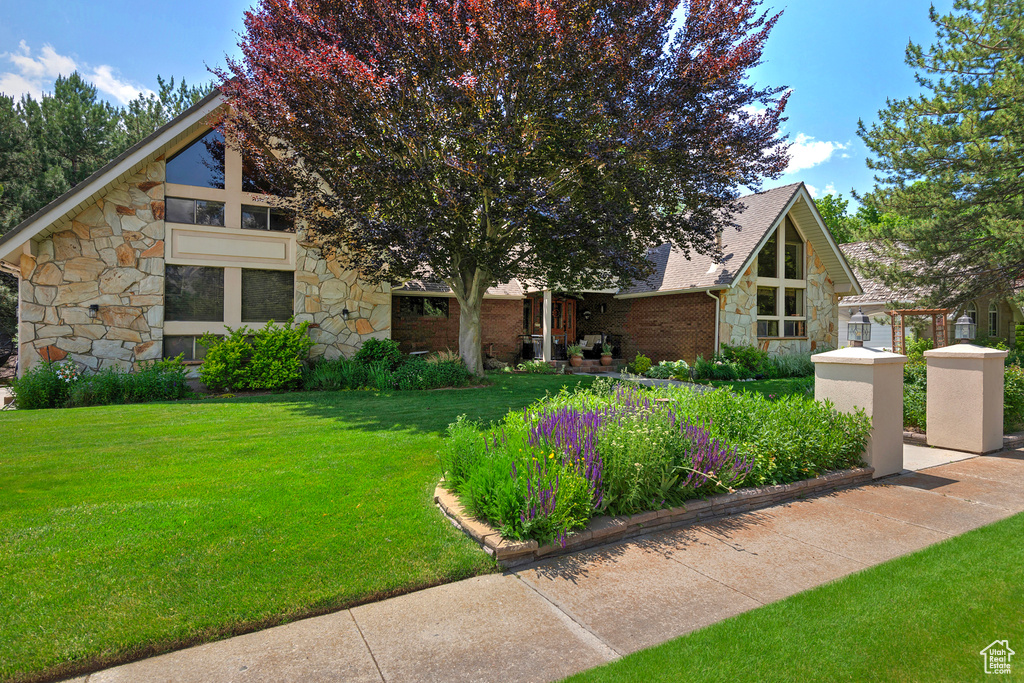 Mid-century home featuring stone siding and a front lawn