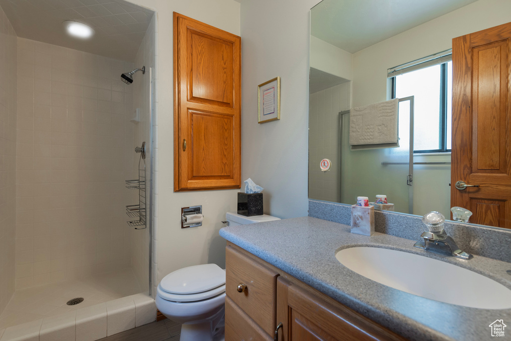 Full bathroom with vanity, tiled shower, and toilet