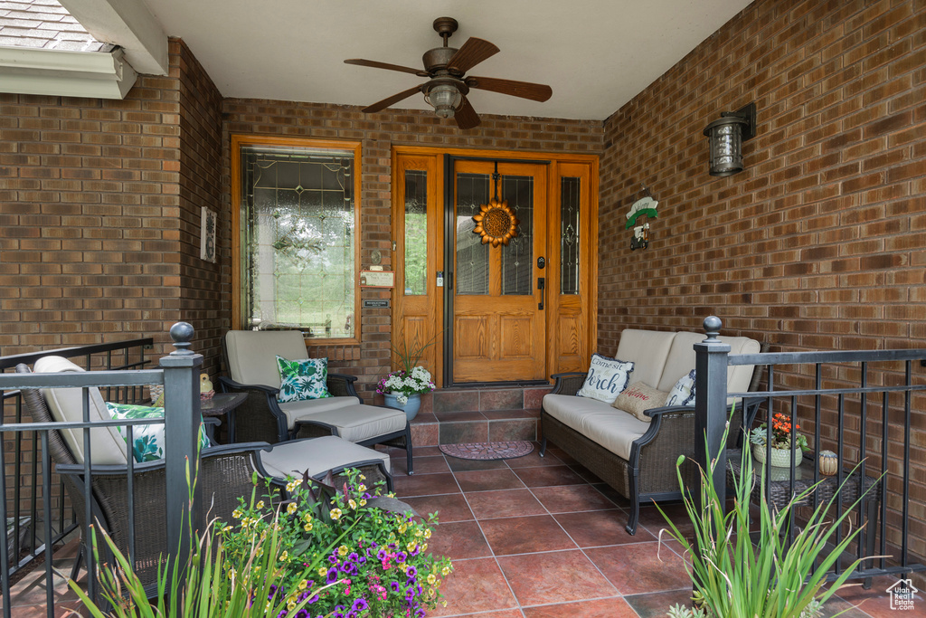 Doorway to property with an outdoor living space, brick siding, a ceiling fan, and a porch