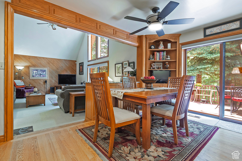 Dining space featuring wooden walls, a ceiling fan, and light wood-style flooring