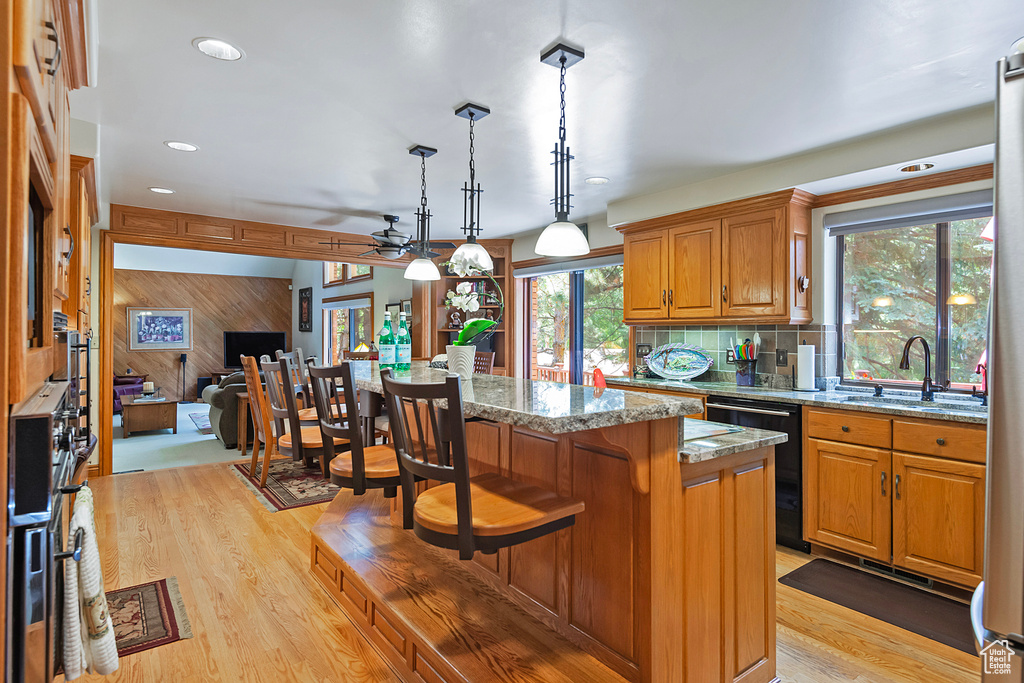 Kitchen with a sink, light wood finished floors, a center island, a kitchen breakfast bar, and brown cabinets