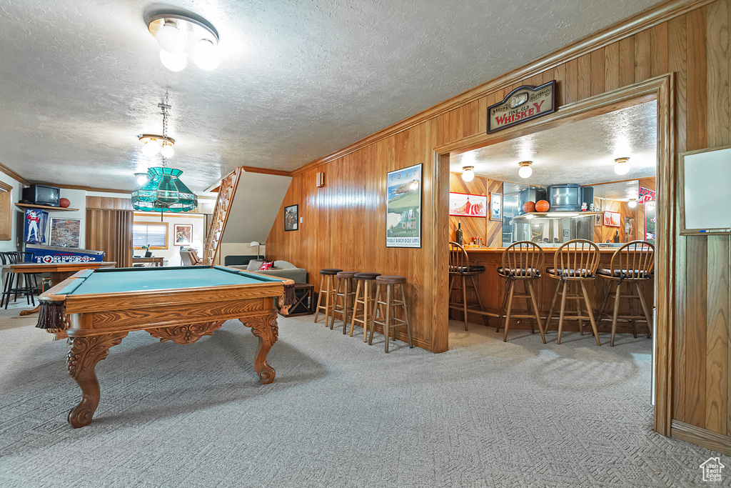 Playroom with a dry bar, carpet floors, wooden walls, billiards, and crown molding