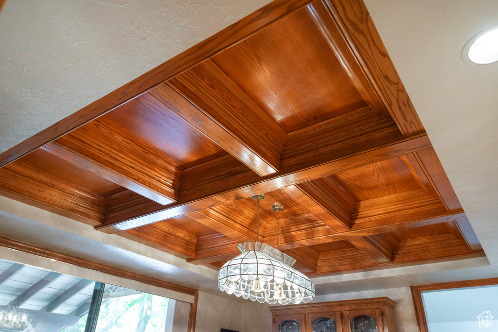 Detailed view of coffered ceiling, wood ceiling with exposed beams, and a chandelier