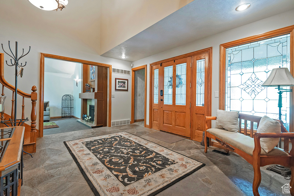 Entryway featuring stone tile flooring, plenty of natural light, a fireplace with raised hearth, baseboards, and recessed lighting