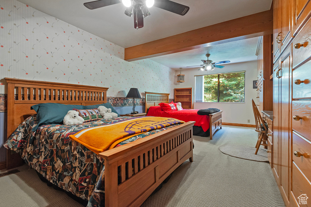 Bedroom featuring carpet, wallpapered walls, baseboards, beamed ceiling, and a ceiling fan