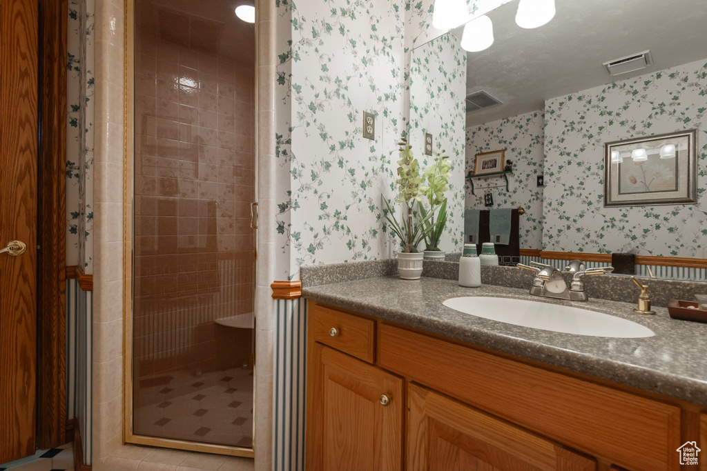 Bathroom with wallpapered walls, a shower stall, and vanity