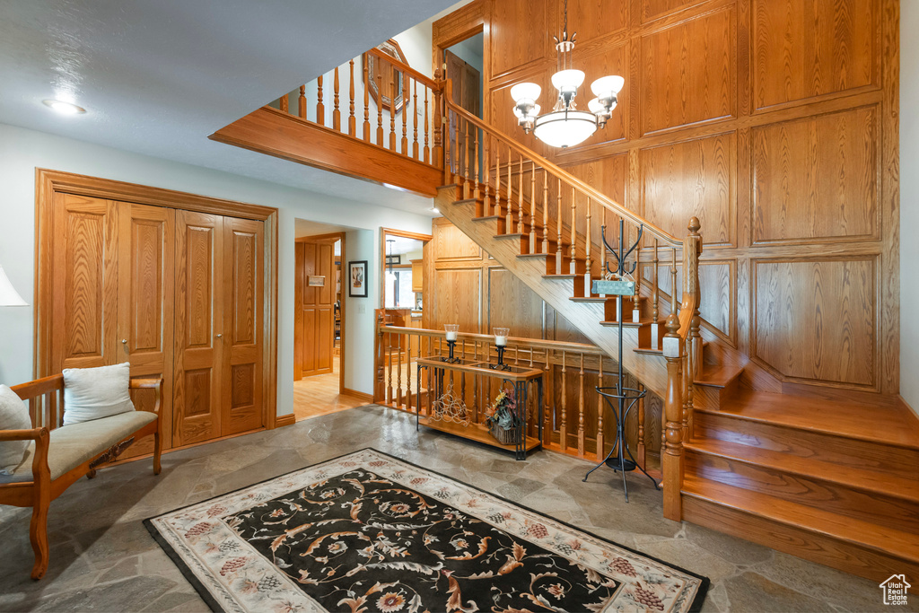Entrance foyer with a chandelier, stairway, and stone finish floors
