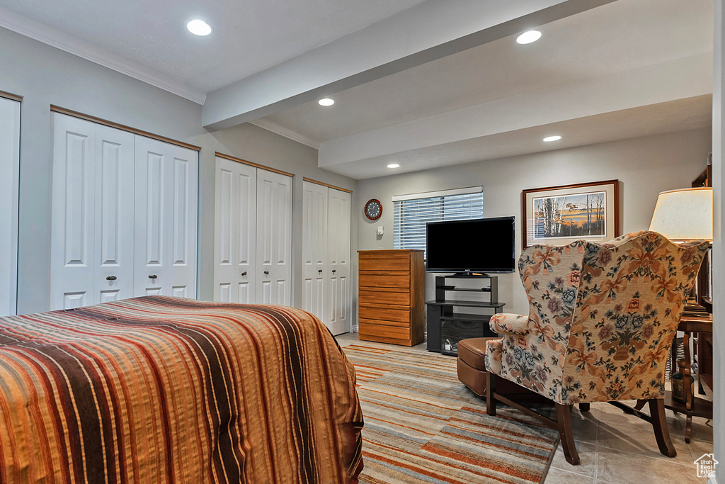 Bedroom featuring two closets, recessed lighting, beamed ceiling, and ornamental molding
