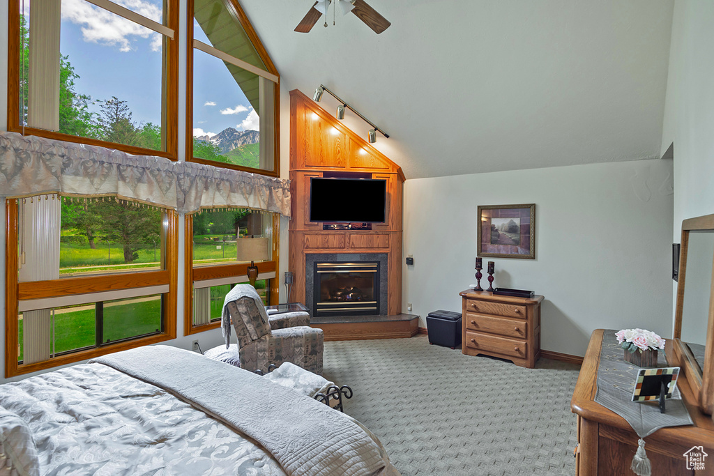 Carpeted bedroom featuring vaulted ceiling, a fireplace, and multiple windows