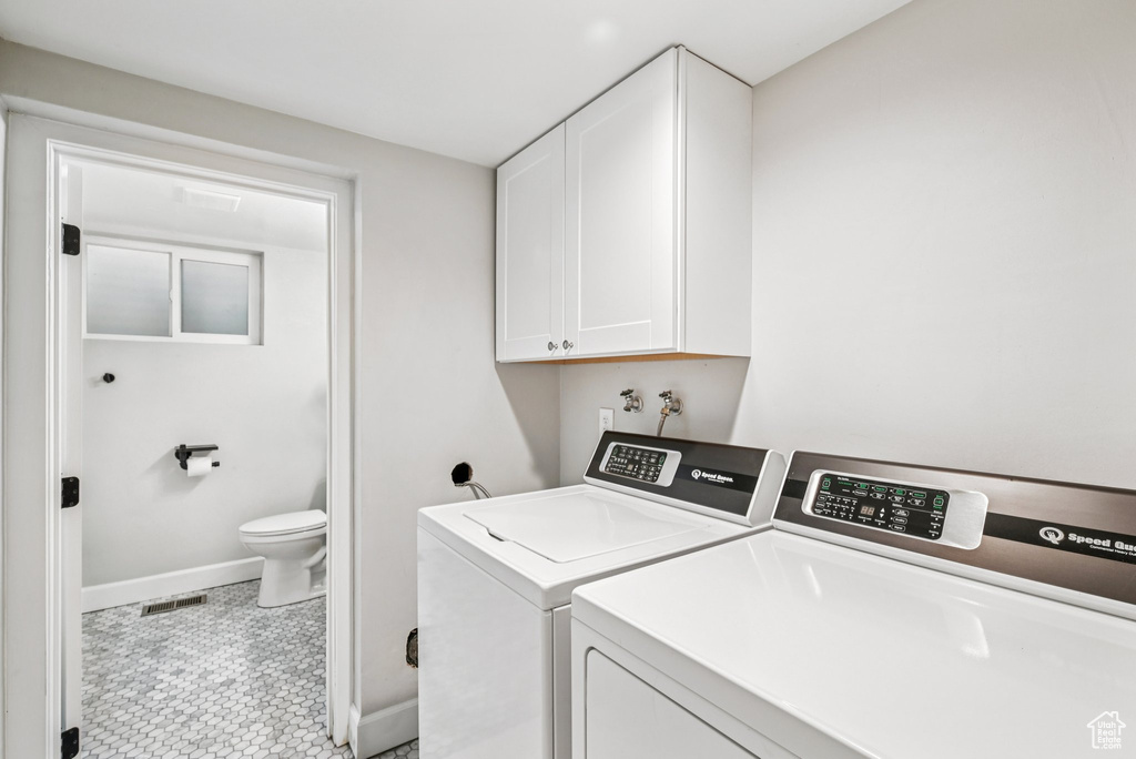 Washroom with cabinet space, washing machine and clothes dryer, and baseboards
