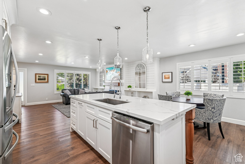 Kitchen with stainless steel appliances, a sink, recessed lighting, open floor plan, and baseboards