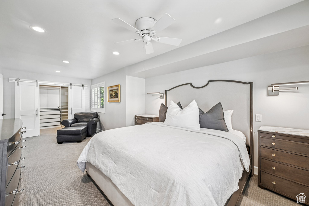 Carpeted bedroom with recessed lighting, a barn door, a ceiling fan, a closet, and a walk in closet