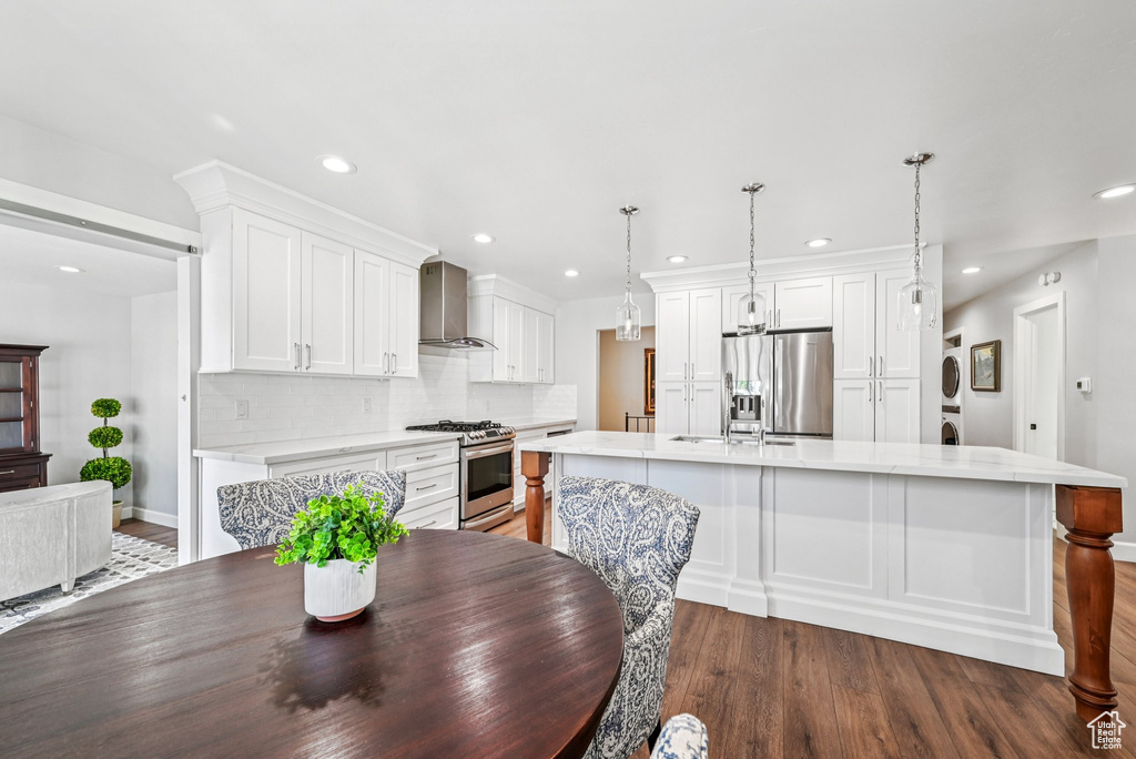Dining room with stacked washer and clothes dryer, wood finished floors, recessed lighting, and baseboards