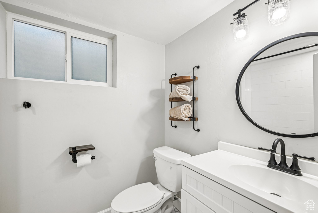 Bathroom with toilet, vanity, and baseboards