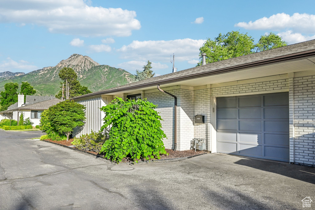 View of property exterior with brick siding, driveway, a mountain view, and a garage