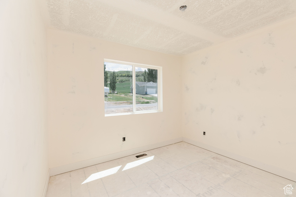 Empty room with a textured ceiling and baseboards