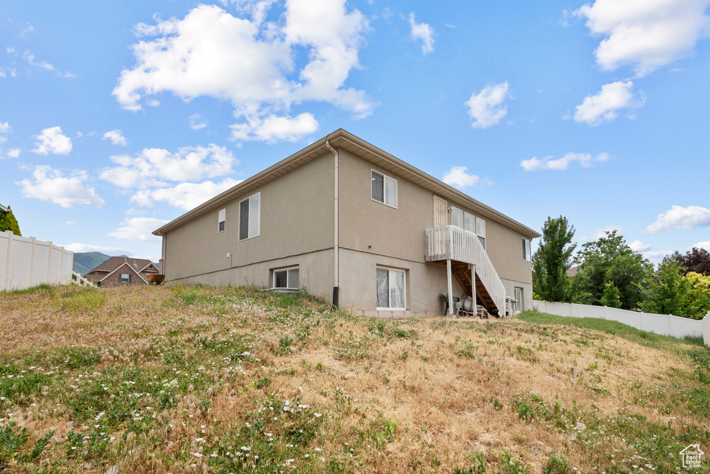 Rear view of property featuring stairway and stucco siding