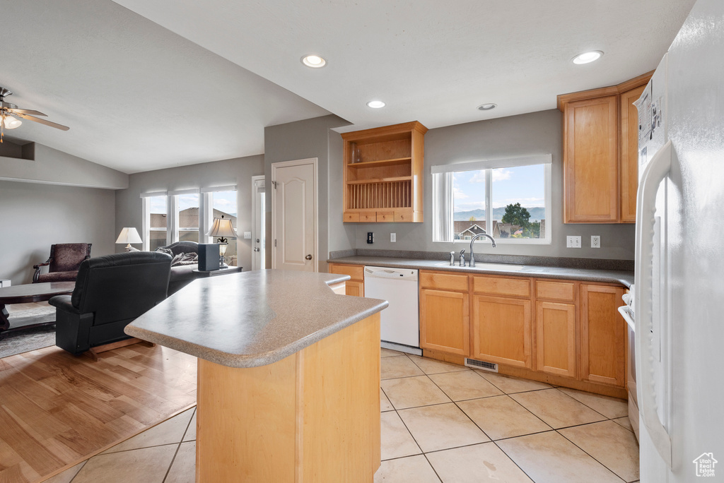 Kitchen featuring white appliances, a kitchen island, open floor plan, light tile patterned floors, and recessed lighting