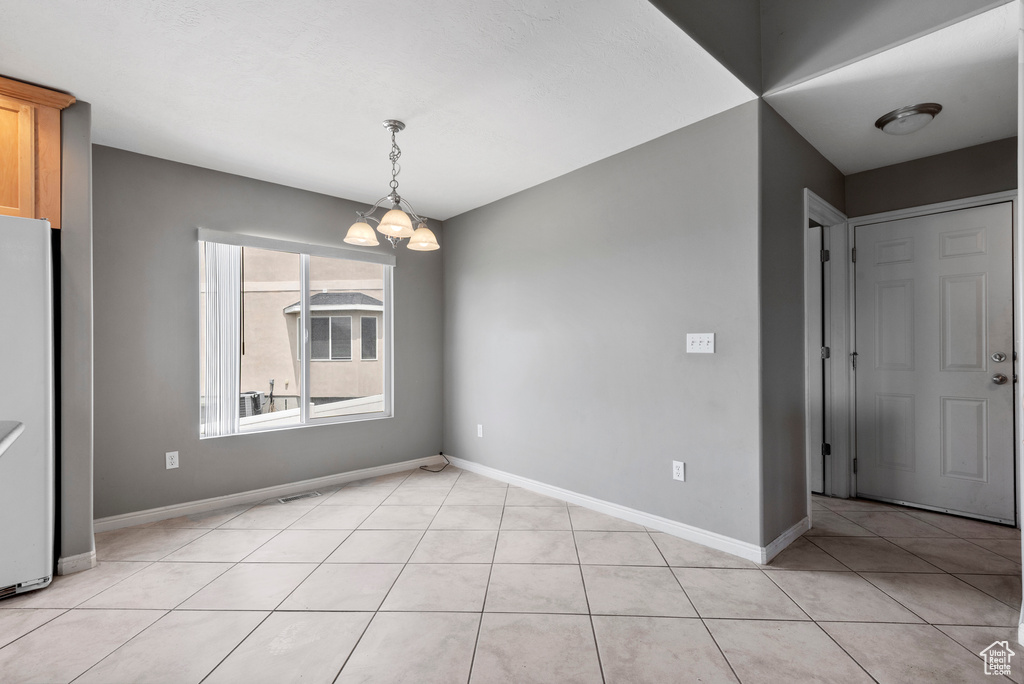 Unfurnished dining area featuring a chandelier and light tile patterned flooring