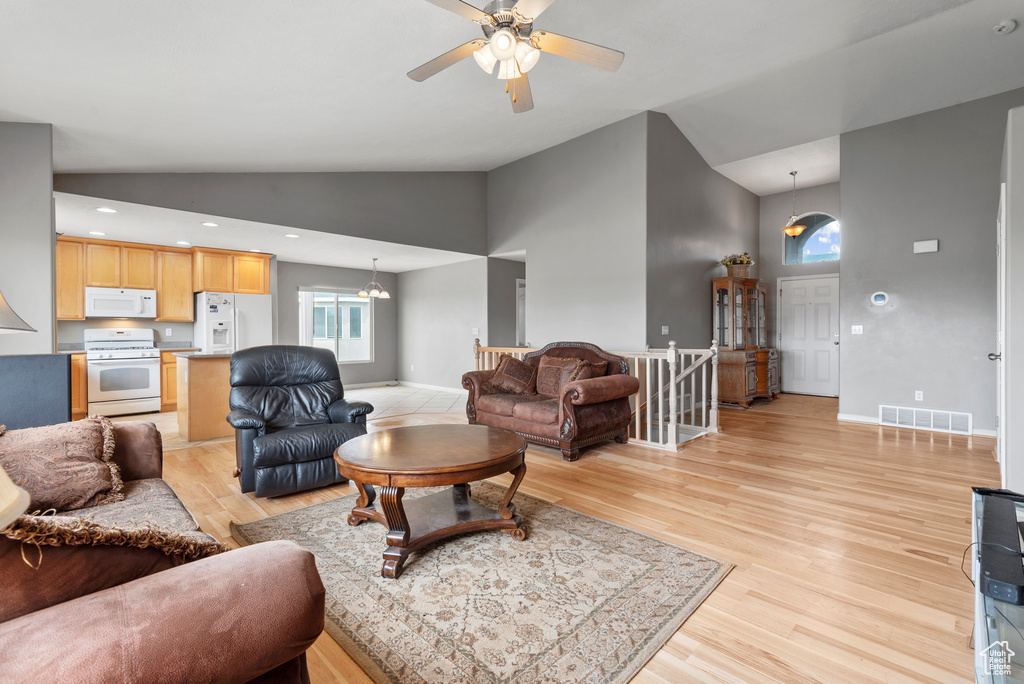Living area featuring high vaulted ceiling, light wood-type flooring, and ceiling fan