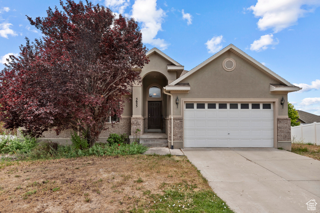 View of front of home with a garage, stucco siding, concrete driveway, and brick siding