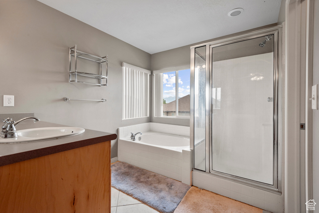 Full bath with a stall shower, a garden tub, tile patterned flooring, and double vanity