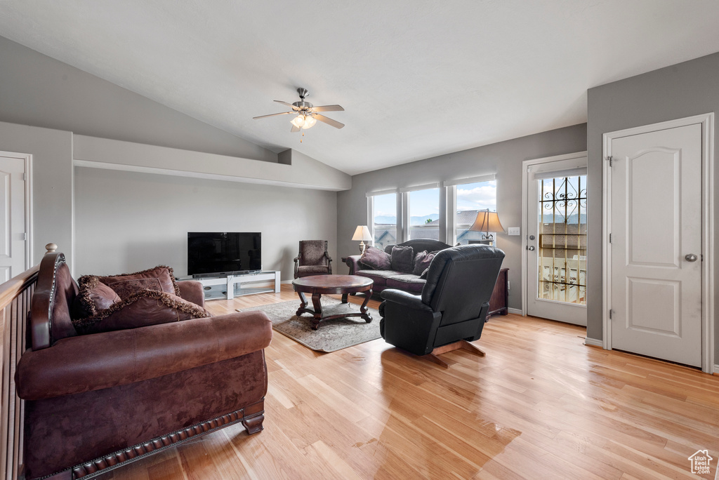 Living area with a ceiling fan, vaulted ceiling, and light wood-type flooring