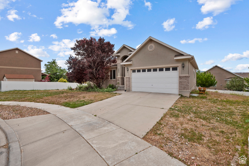 View of front of property with a garage, driveway, and stucco siding