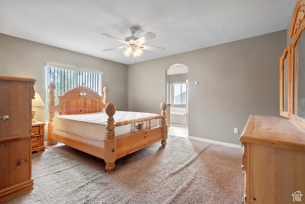 Bedroom with arched walkways, light colored carpet, and a ceiling fan