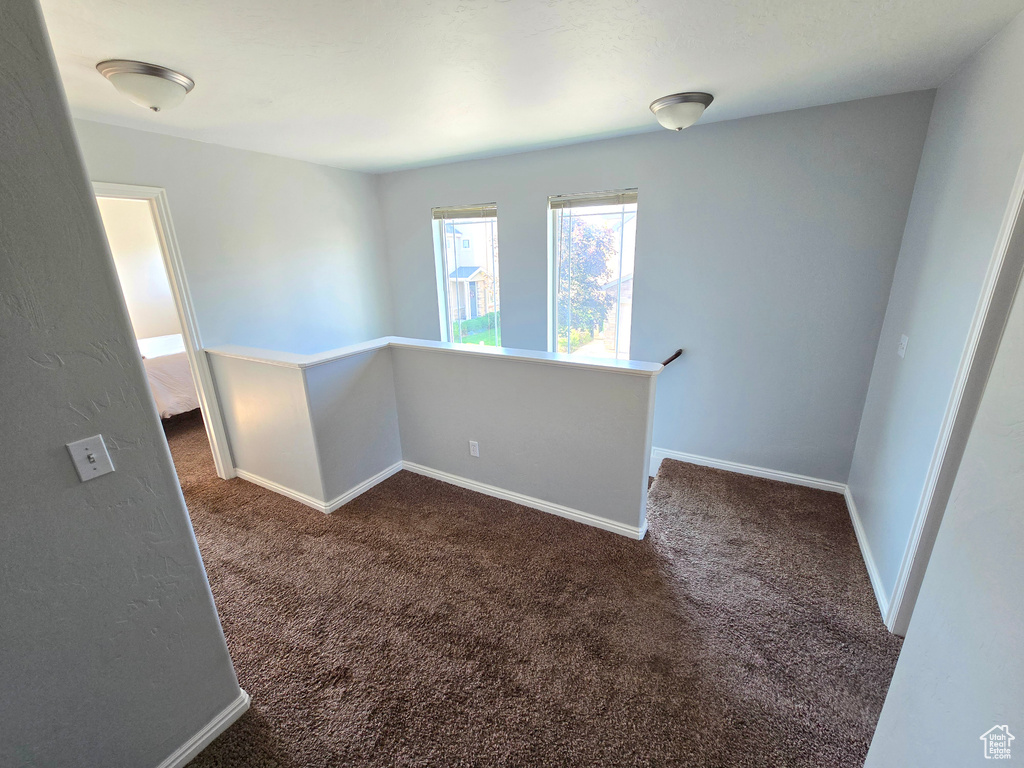 Spare room with dark carpet and baseboards