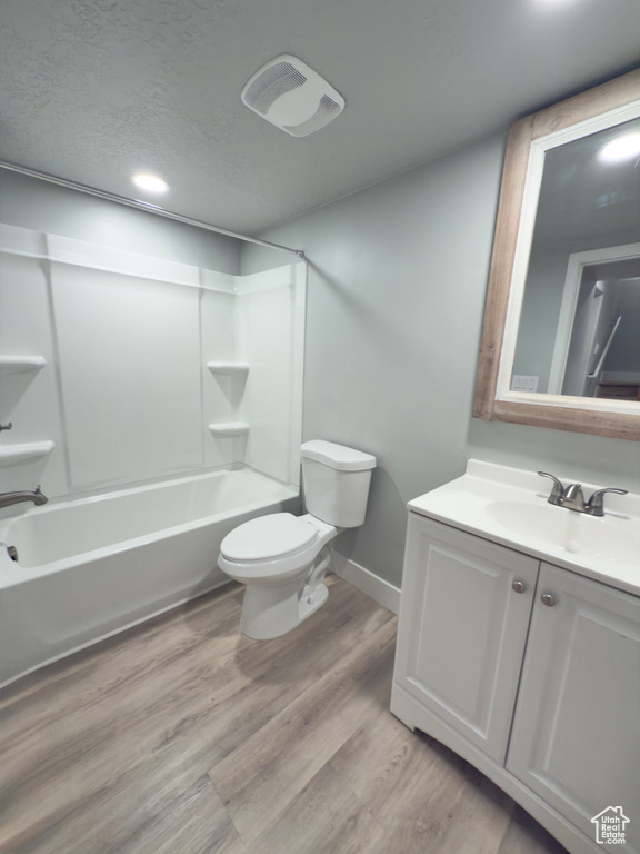Bathroom with vanity, shower / bathtub combination, wood finished floors, recessed lighting, and a textured ceiling