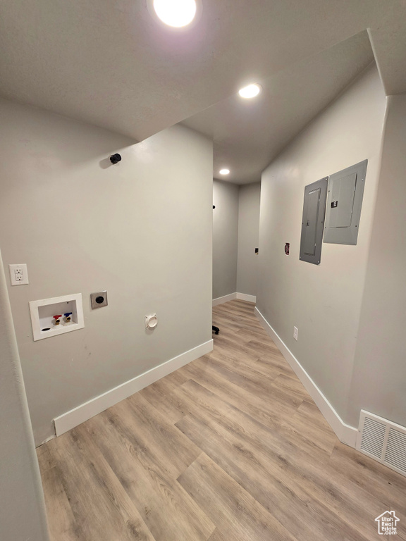 Washroom with electric panel, hookup for a washing machine, hookup for an electric dryer, light wood-type flooring, and recessed lighting