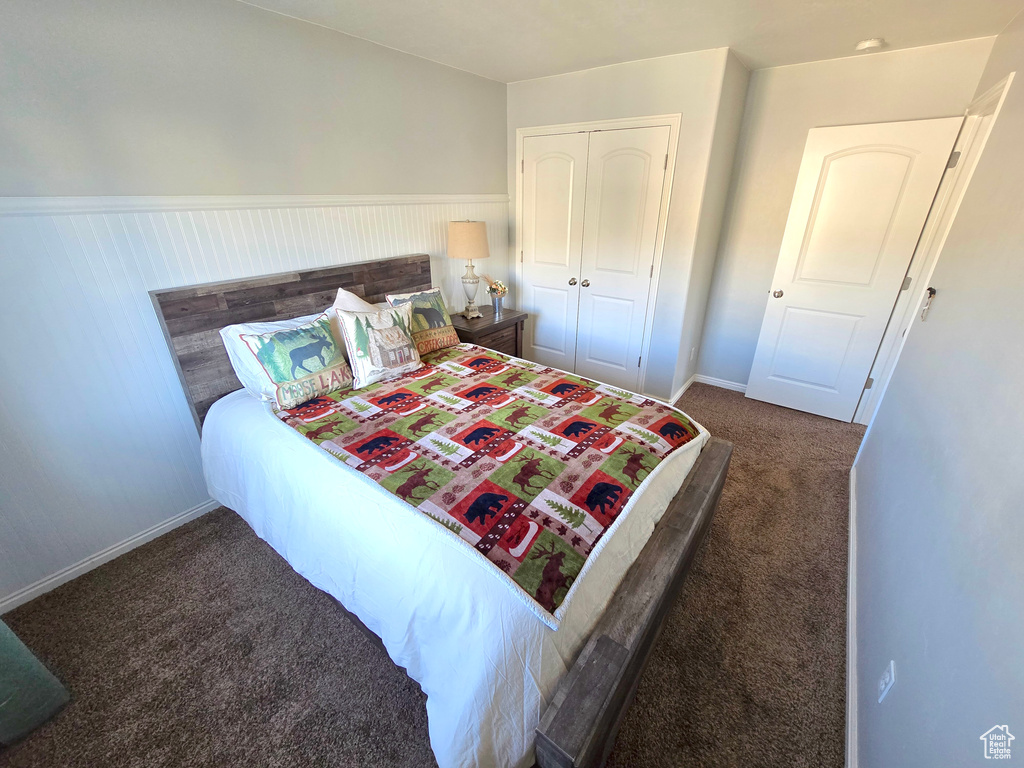 Carpeted bedroom featuring wainscoting, a closet, and baseboards